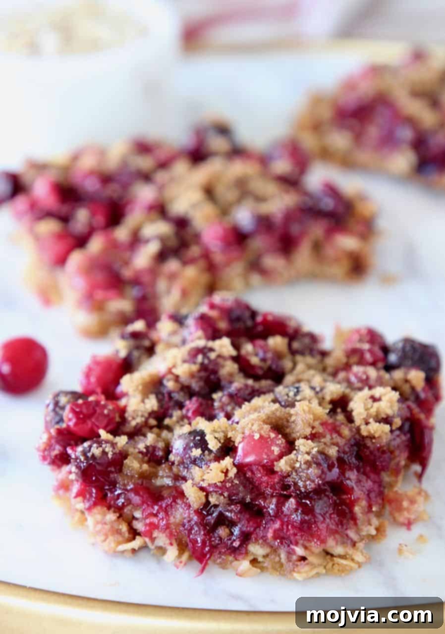 Delicious Oatmeal Cranberry Bars cut into squares on a elegant marble serving tray, showcasing layers of oats and bright red cranberries.