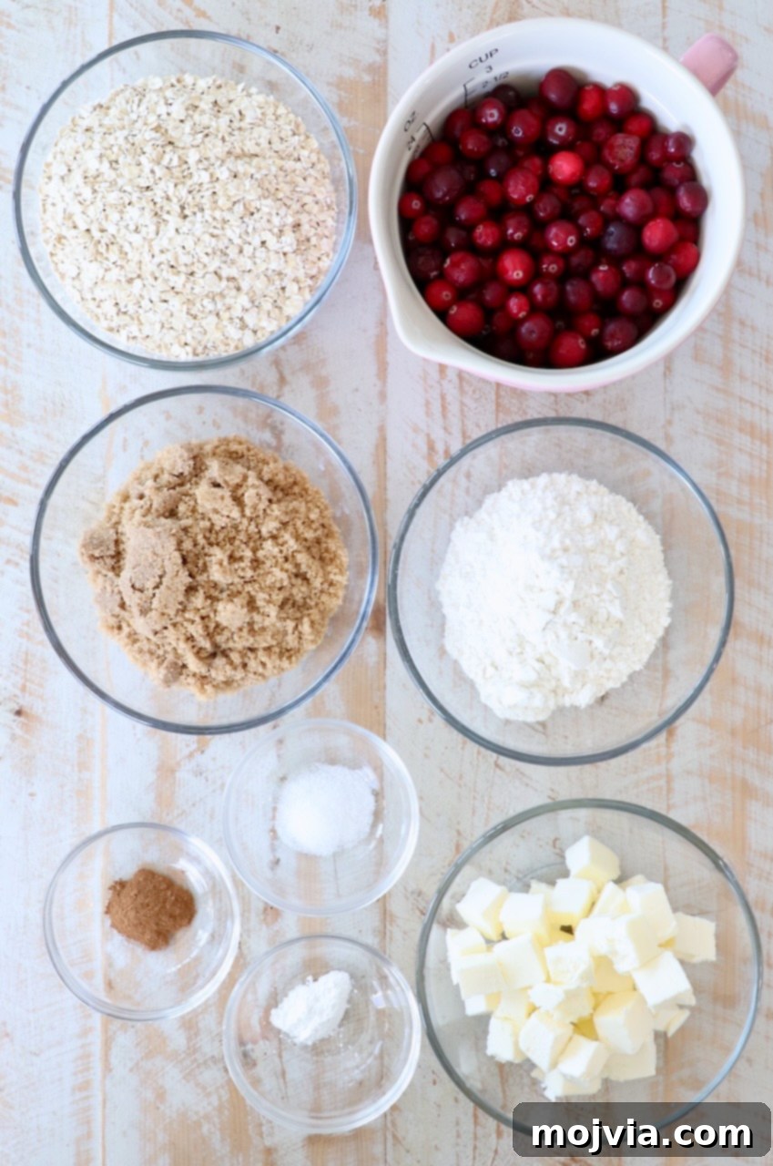 Arrangement of ingredients for Oatmeal Cranberry Bars on a white wooden board, featuring flour, brown sugar, oats, butter, and fresh cranberries.