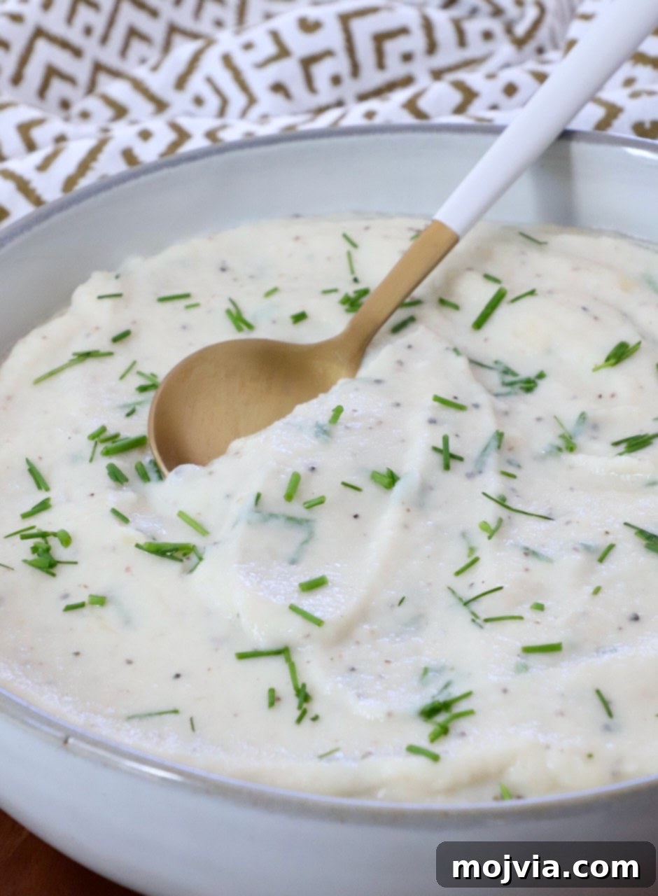 Creamy Cauliflower Mash 7 A bowl of creamy mashed cauliflower with a spoon, ready to be served.