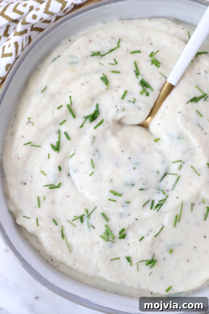 Creamy Cauliflower Mash 8 A bowl of creamy mashed cauliflower with a spoon, ready to be served and enjoyed as a delicious side dish.