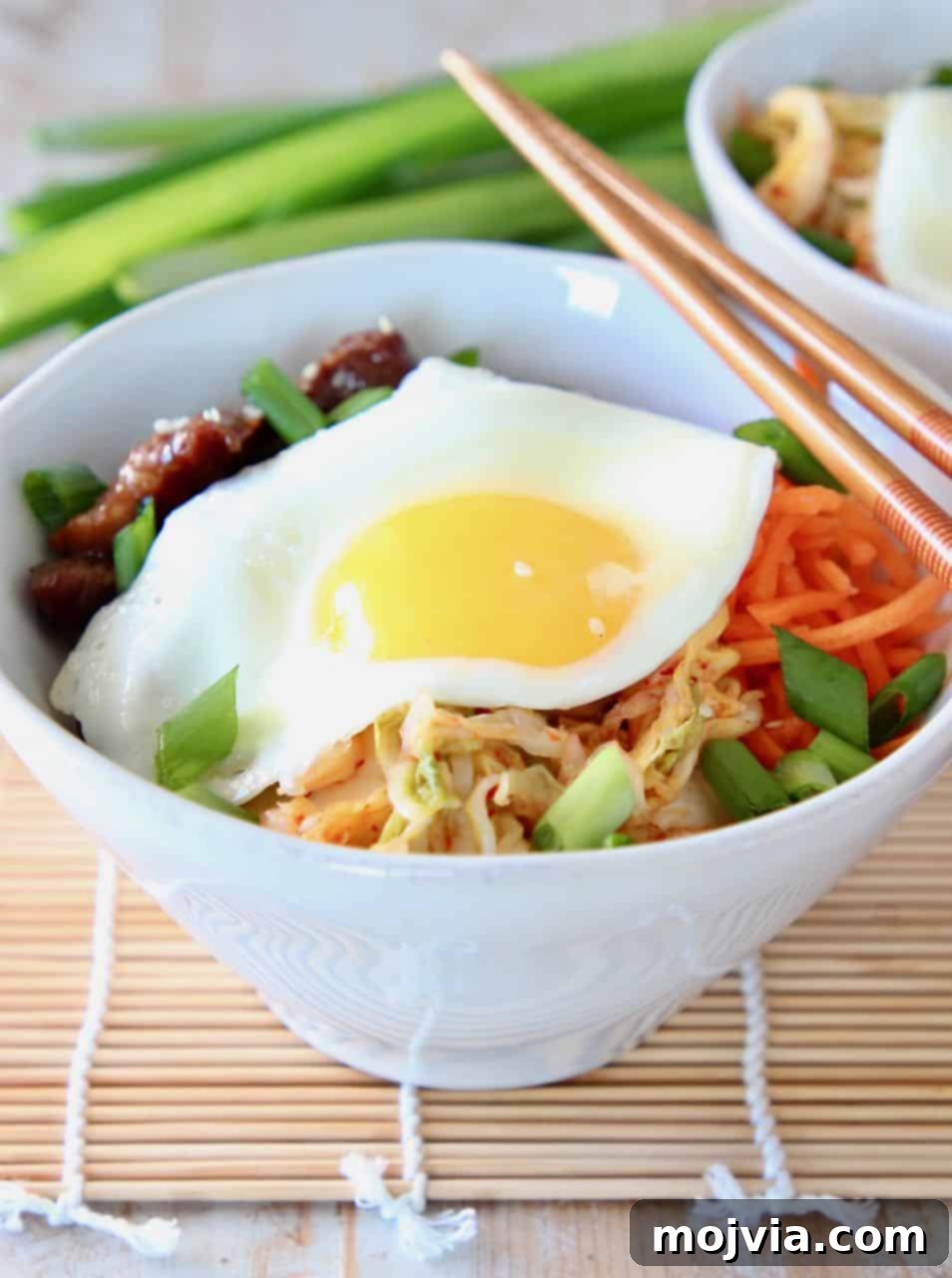 Korean BBQ Cauliflower Rice Bowl topped with a fried egg and chopsticks