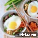 Cauliflower rice bowls topped with fried eggs and shredded carrots