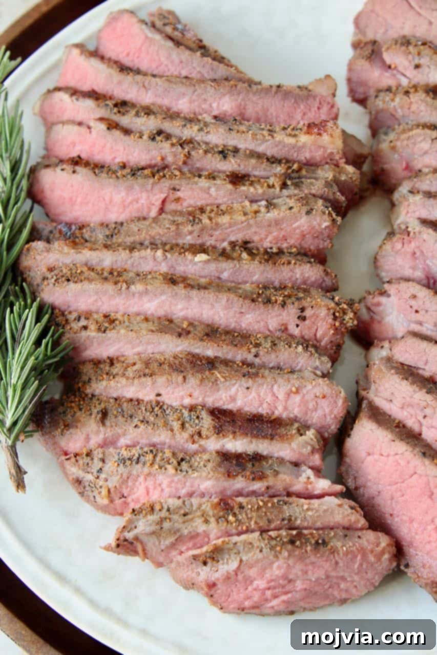 Perfectly Tender Sous Vide Tri Tip 2 Perfectly Sliced Sous Vide Tri Tip Steak on a Plate with Fresh Rosemary Garnish