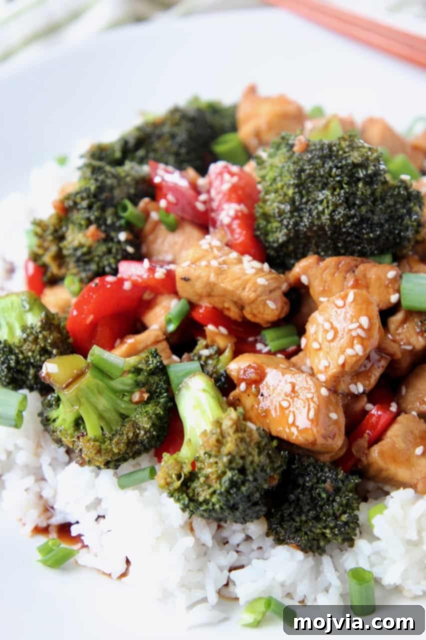 Sticky Teriyaki Chicken Stir Fry 4 Individual pieces of teriyaki chicken and broccoli florets arranged over a serving of rice on a white plate.