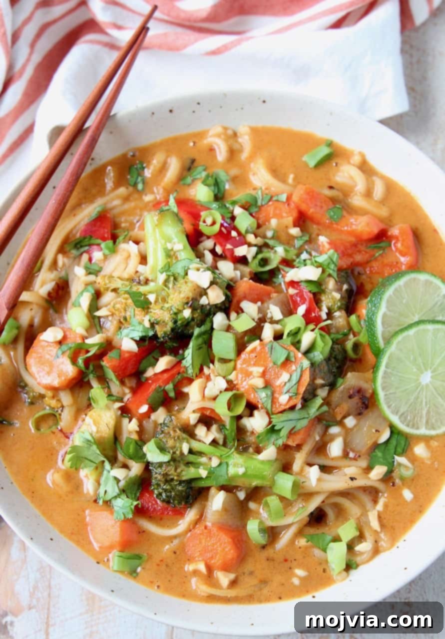 Overhead image of vegetable massaman curry in bowls with noodles and lime wedges