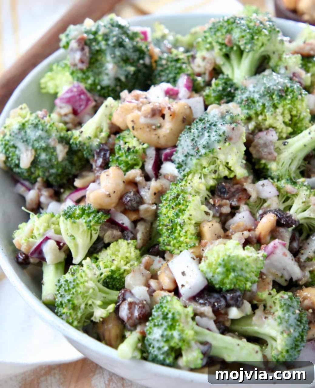 Freshly prepared broccoli salad with bacon, raisins, and cashews in a white serving bowl, ready for a BBQ or party.