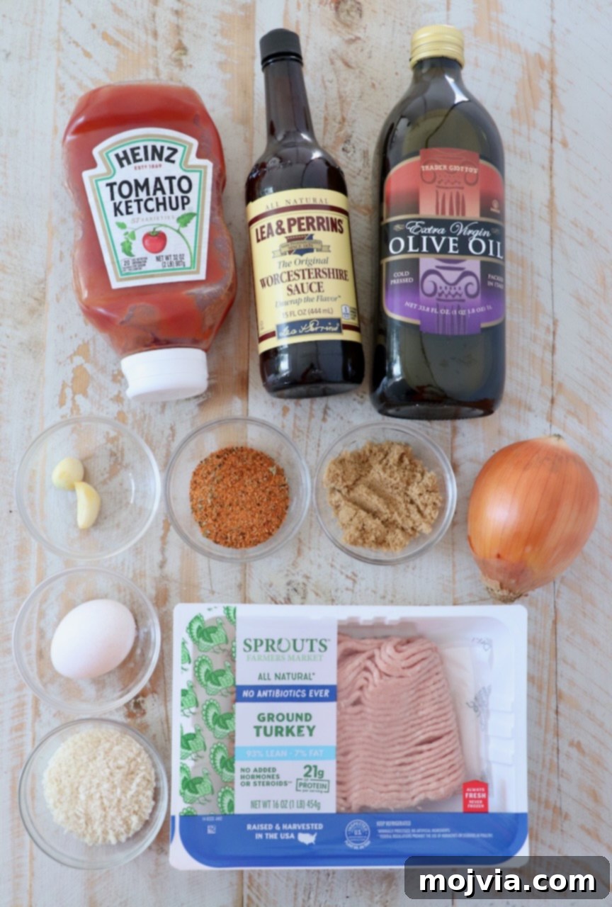 Assortment of fresh ingredients for mini meatloaves laid out on a white wooden surface.