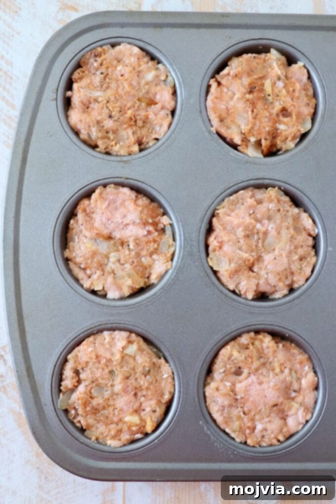 Prepared ground turkey meatloaf mixture pressed neatly into a muffin tin, ready for baking.