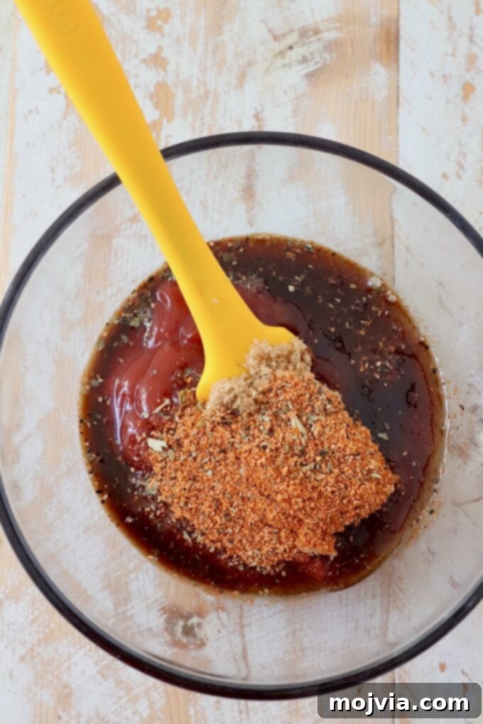Ingredients for homemade BBQ sauce including spices, ketchup, and Worcestershire sauce in a small glass bowl.