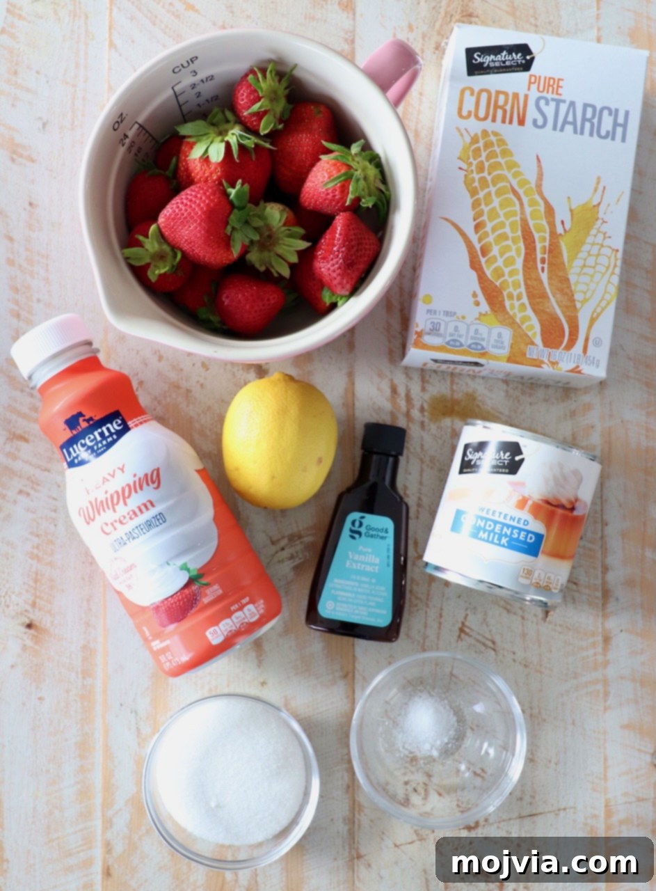 Various ingredients for no churn strawberry ice cream laid out on a white wooden board