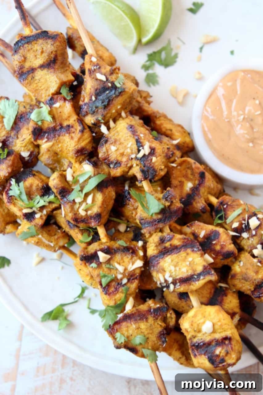 Savory Thai Chicken Satay with Creamy Peanut Sauce 2 Skewers of chicken on plate with small bowl of peanut sauce