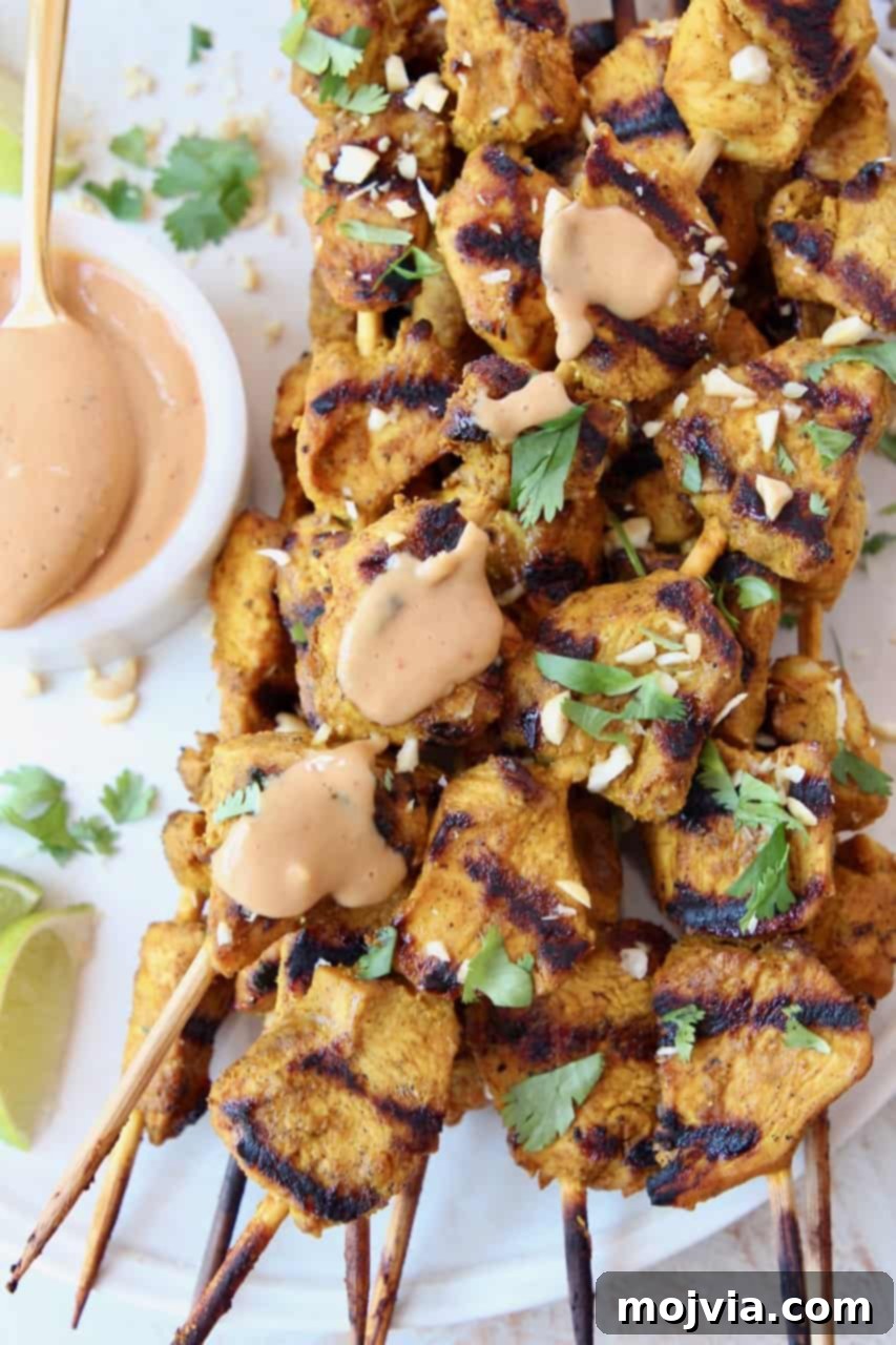 Savory Thai Chicken Satay with Creamy Peanut Sauce 5 grilled chicken skewers on plate with peanut sauce