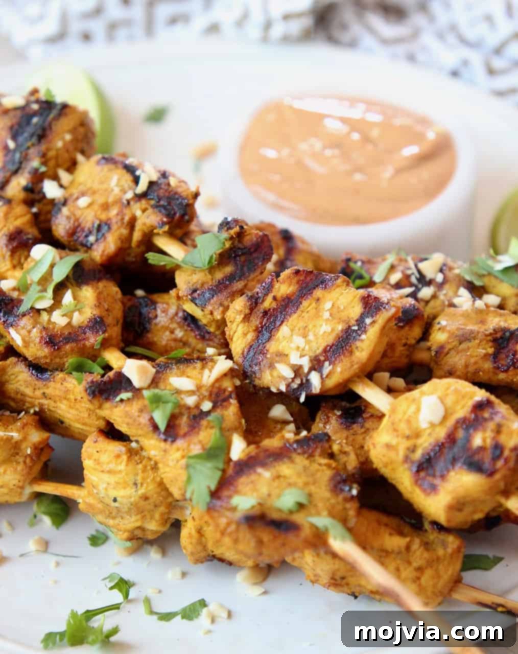 Savory Thai Chicken Satay with Creamy Peanut Sauce 6 Grilled chicken satay on plate with bowl of peanut sauce