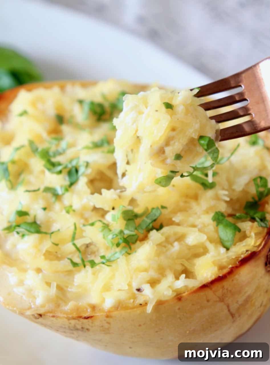 Golden Spaghetti Squash Mac and Cheese Bake 2 Spaghetti squash mac and cheese in a squash shell with fork dipped into the squash, showcasing its creamy texture