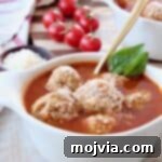 Five-Ingredient Italian Meatball Magic 6 Meatball soup in bowl with gold spoon and fresh basil leaves