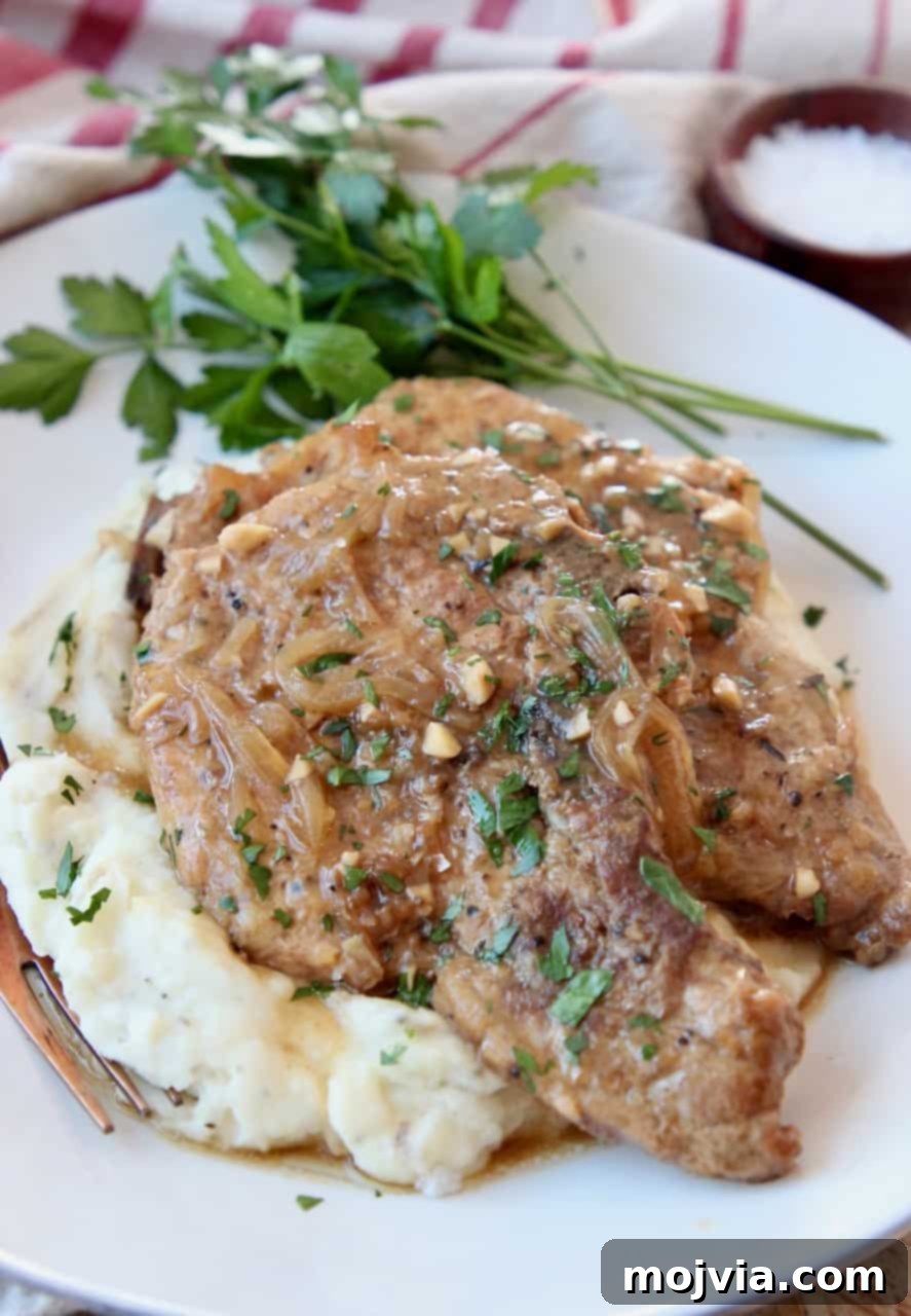 Slow Cooker French Onion Pork Chops 2 Stack of tender French Onion Crock Pot Pork Chops on a bed of mashed potatoes, drizzled with savory gravy