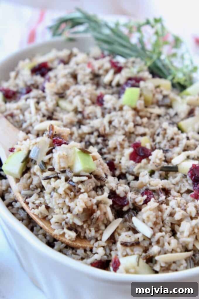 Jeweled Wild Rice Pilaf with Apples and Cranberries 5 Close-up image of the prepared Wild Rice Pilaf in a festive serving dish, adorned with fresh herbs, ready for serving.