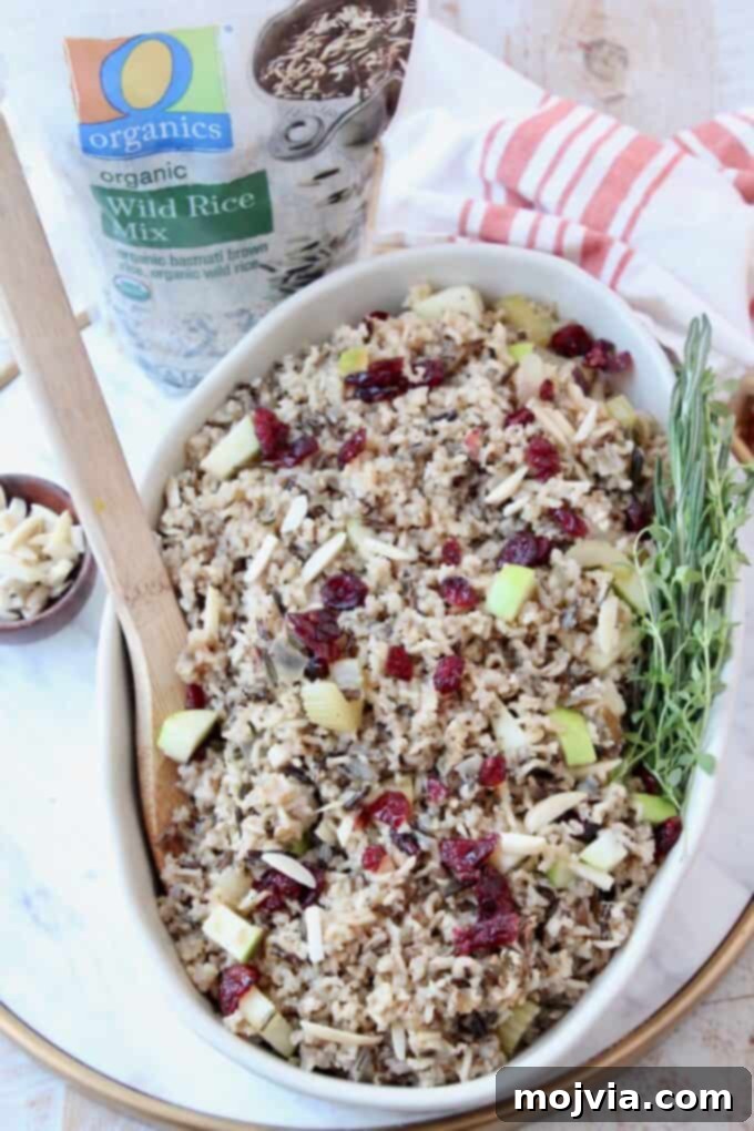 Jeweled Wild Rice Pilaf with Apples and Cranberries 6 A vibrant image of cooked wild rice pilaf in a serving dish, ready to be enjoyed, with fresh herbs scattered on top.