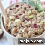 Wild Rice Pilaf with Apples & Cranberries in a serving dish with a wooden spoon.