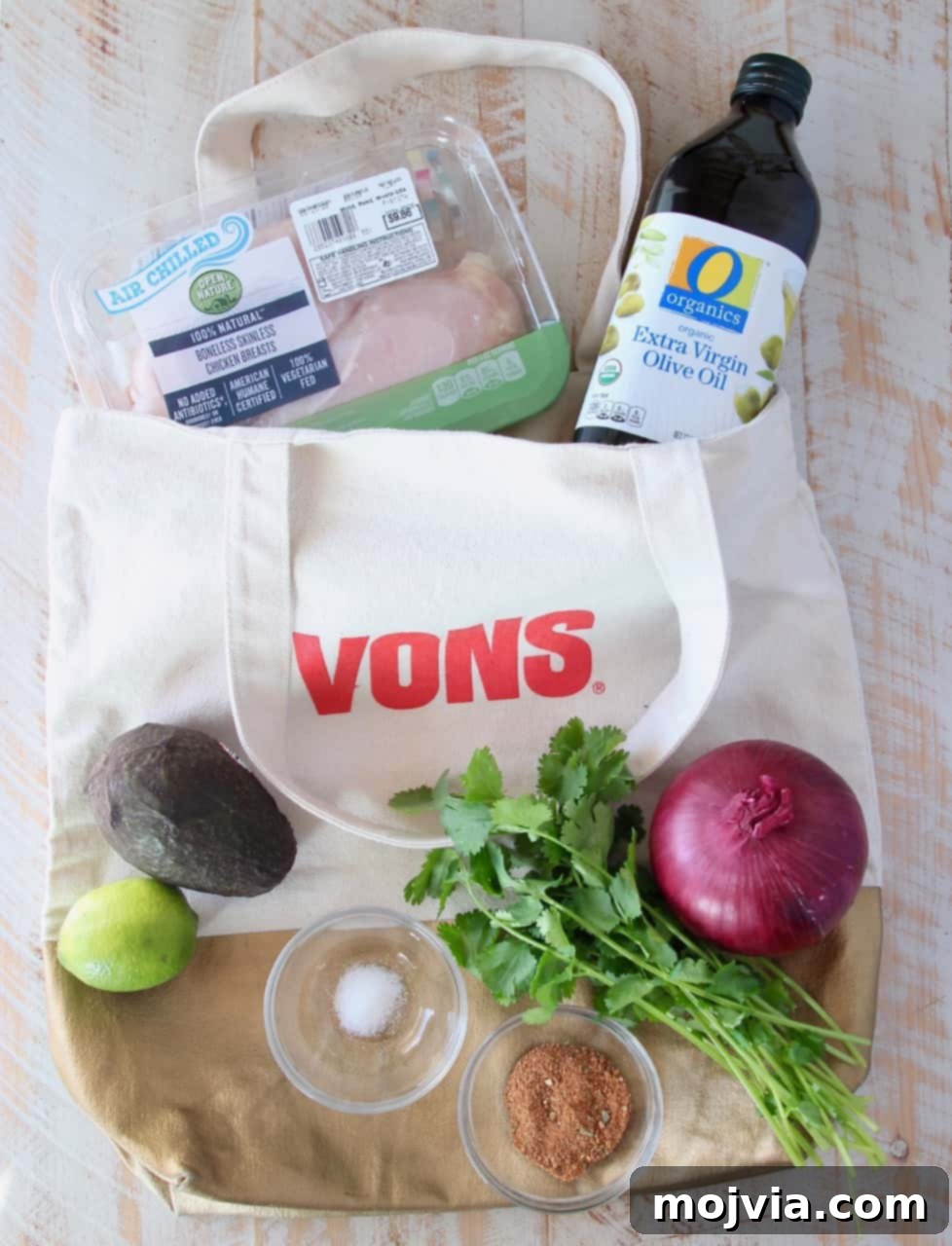 Ingredients for guacamole stuffed chicken laid out on a white wooden board
