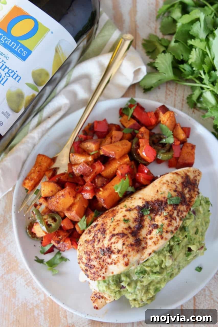 Overhead shot of guacamole stuffed chicken on a plate with roasted vegetables, ready to eat