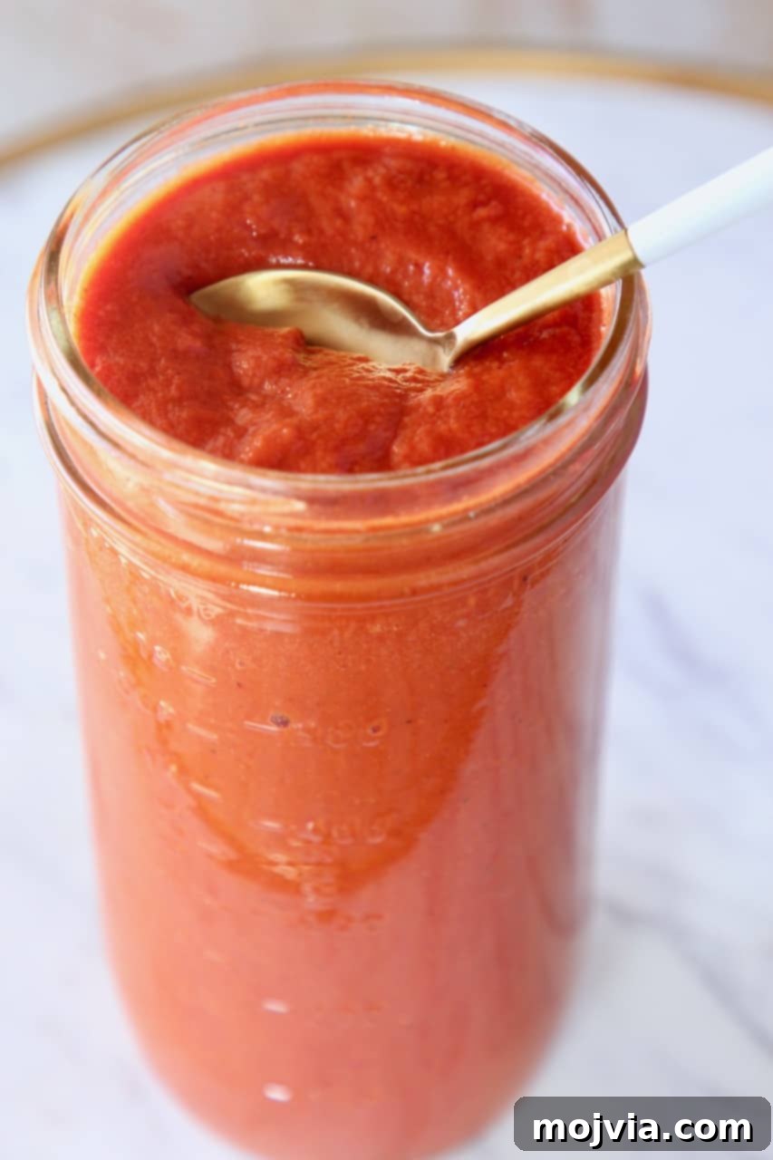 Classic Red Enchilada Sauce 2 spoon in mason jar of enchilada sauce