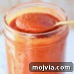 Classic Red Enchilada Sauce 9 spoon of enchilada sauce lifted out of mason jar of sauce