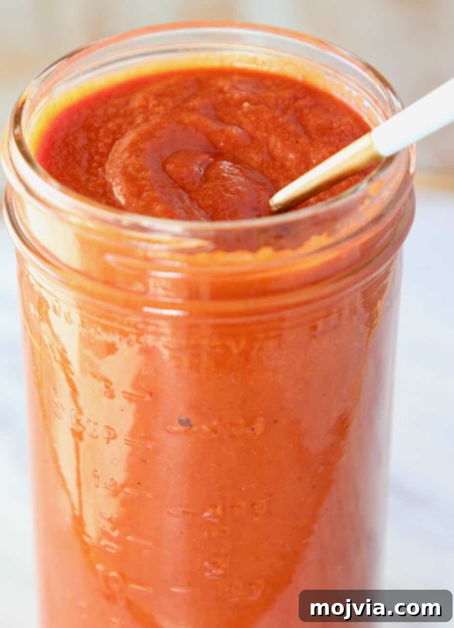 Classic Red Enchilada Sauce 8 spoon in mason jar of enchilada sauce