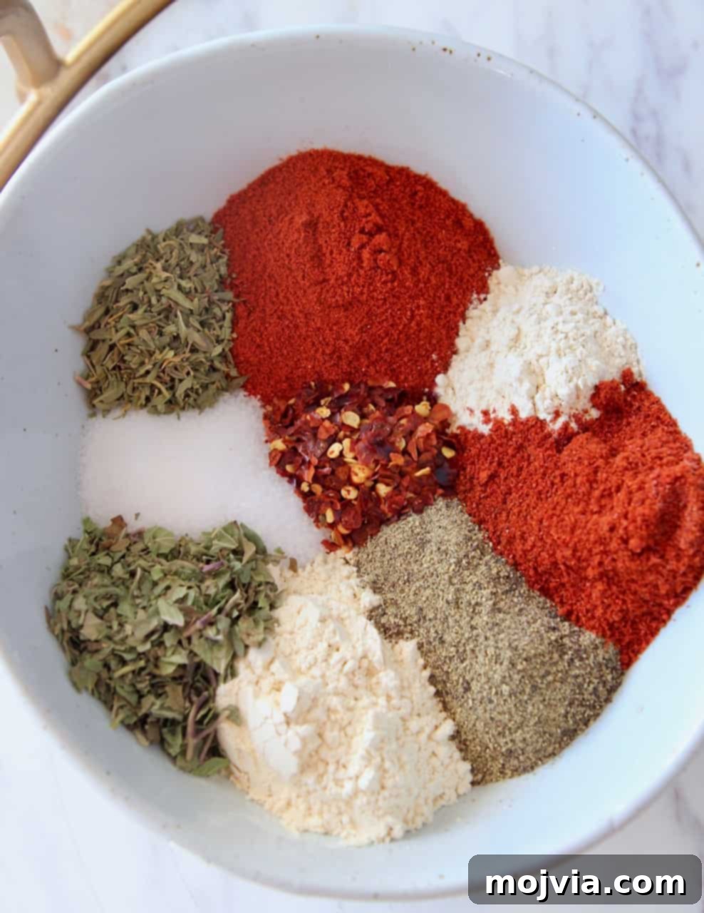 Bayou Blast Seasoning 3 Various spices in a white bowl, ready to be mixed into Cajun seasoning