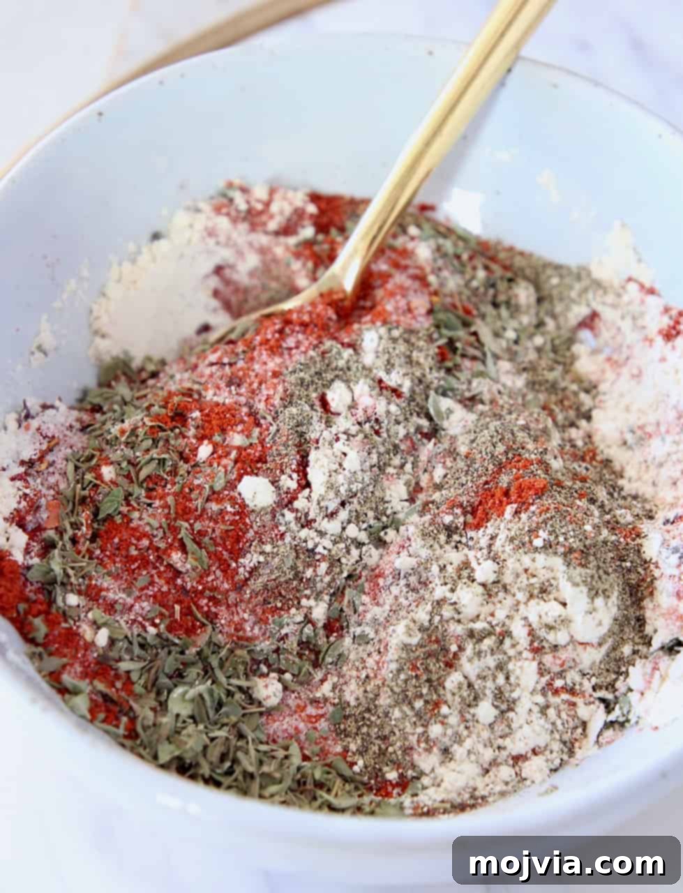 Bayou Blast Seasoning 4 Close-up of freshly mixed Cajun seasoning in a bowl with a gold spoon, highlighting its vibrant colors and textures