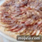 Cinnamon Streusel Apple Dessert Pizza 8 Sliced apples on pizza with cinnamon streusel topping and icing drizzle.