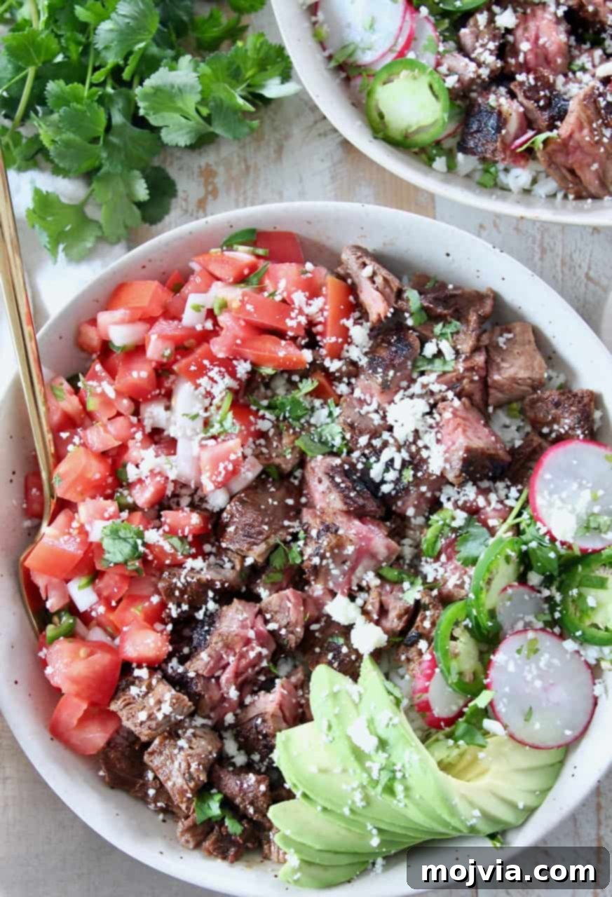 Loaded Carne Asada Bowl 2 Grilled steak in bowl with diced tomatoes and sliced avocado, drizzled with creamy sauce