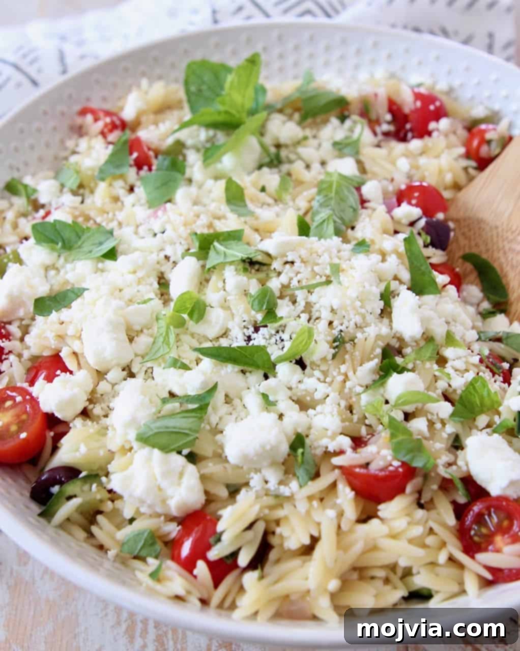 Bright Mediterranean Orzo Salad 9 Close-up of Greek Orzo Pasta Salad in a bowl, topped with fresh mint leaves and crumbled feta cheese.