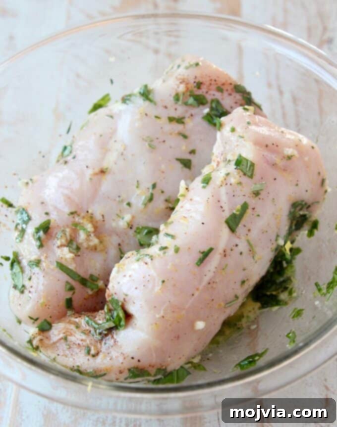 Bright Lemon & Rosemary Chicken 4 chicken breasts soaking in a vibrant lemon herb marinade in a bowl