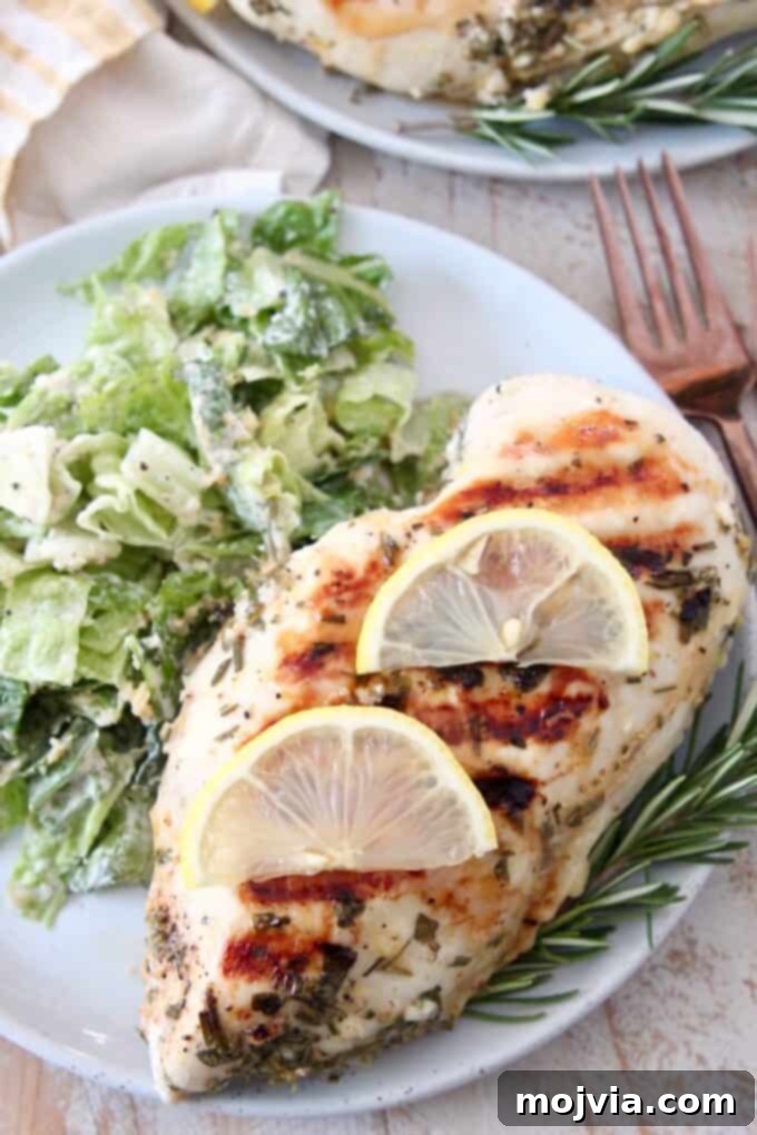 Bright Lemon & Rosemary Chicken 6 overhead image of a sliced grilled chicken breast with lemon slices on the side