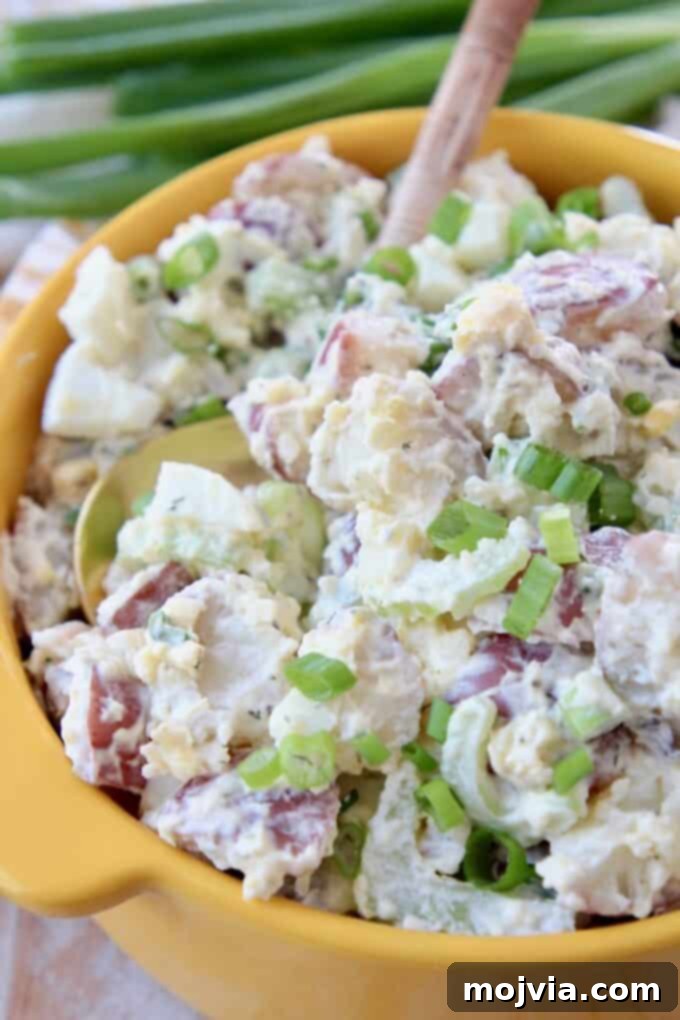Quick and Creamy Instant Pot Cheddar Ranch Potato Salad 2 Delicious Instant Pot Potato Salad with sharp cheddar and ranch in a yellow bowl with a serving spoon.
