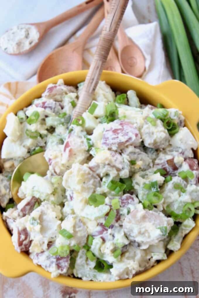 Quick and Creamy Instant Pot Cheddar Ranch Potato Salad 7 The ultimate Cheddar Ranch Instant Pot Potato Salad presented in a yellow bowl, garnished with fresh green onions.