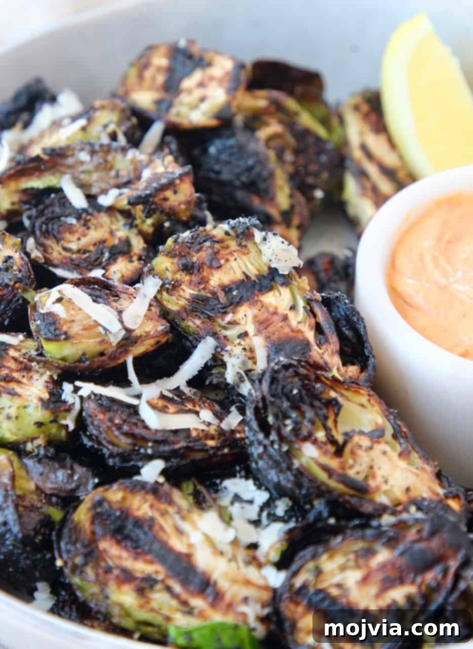 Fire-Kissed Brussels Sprouts 2 grilled brussels sprouts in bowl with lemon wedge and harissa tahini sauce