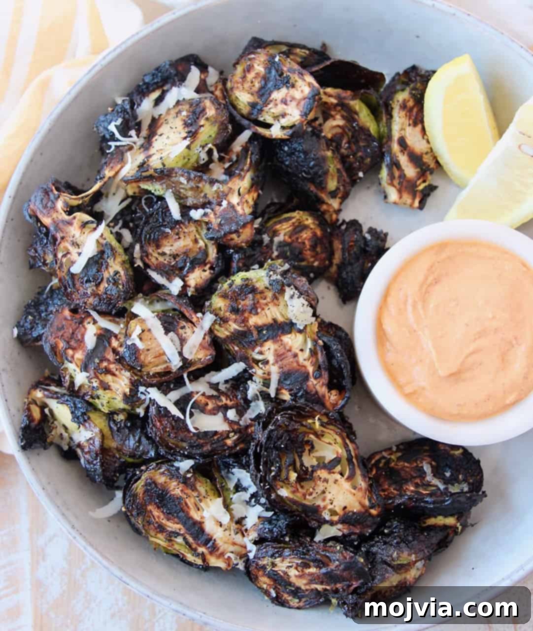 Fire-Kissed Brussels Sprouts 7 grilled brussels sprouts in bowl with harissa tahini dipping sauce on the side