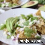 Zesty Verde Chilaquiles 7 A serving of Chilaquiles Verdes on a white plate, garnished with fresh cilantro and sliced avocado, highlighting the vibrant green sauce.