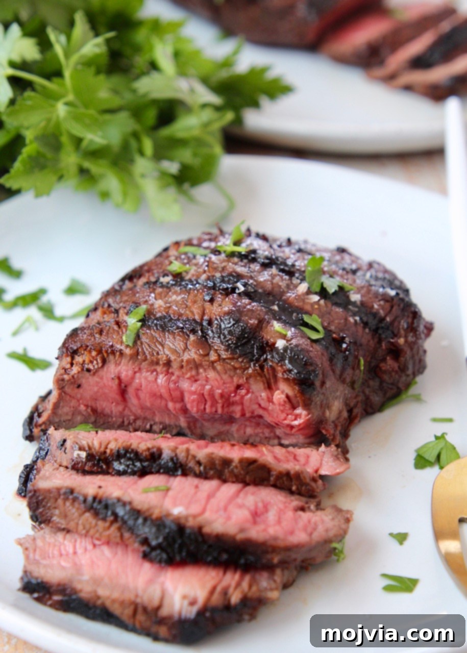 Sirloin Steak Marinade for Tender Perfection 2 sliced grilled steak on plate, topped with fresh chopped parsley