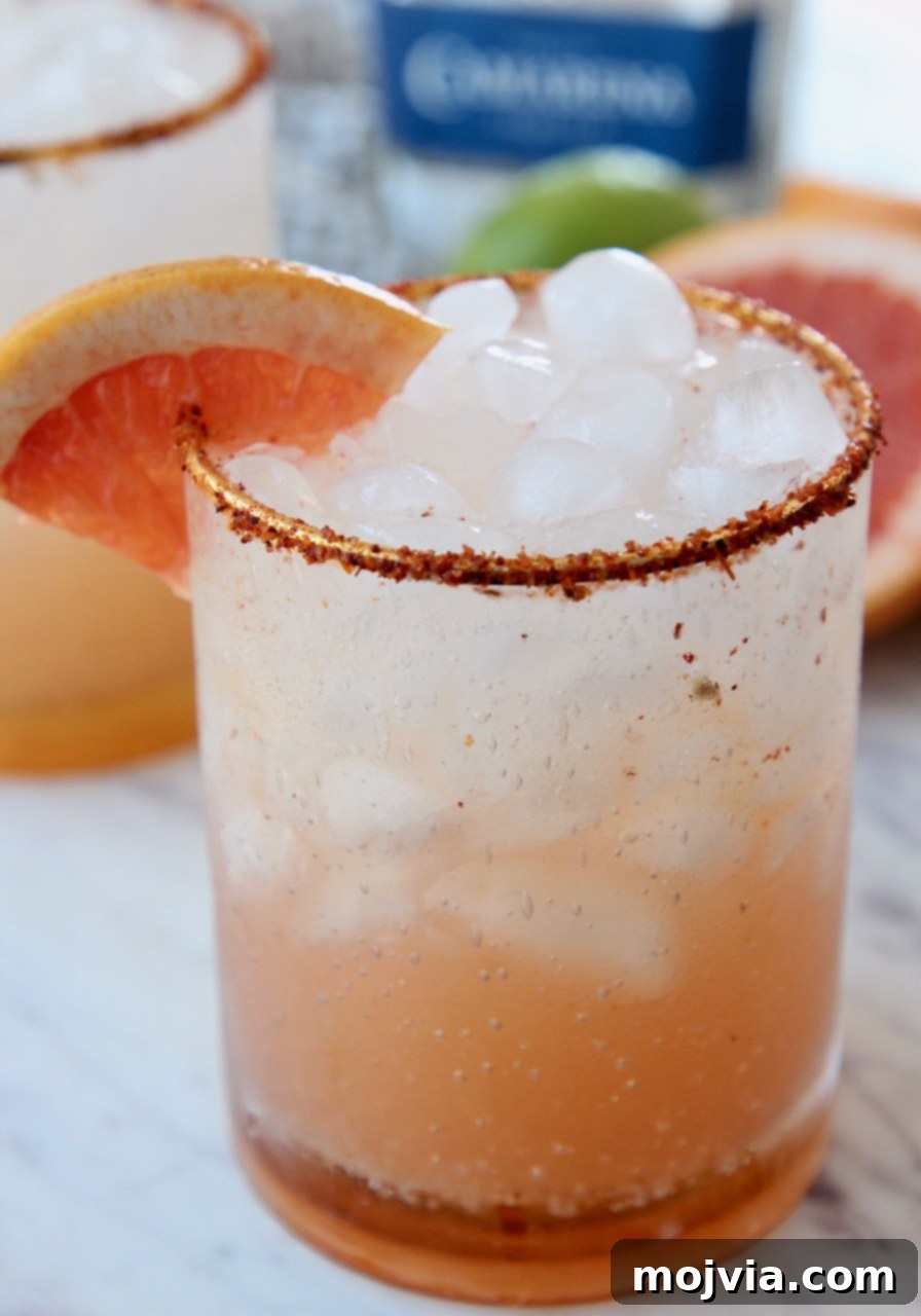 Whispers of Paloma 4 Close-up of a Paloma cocktail with a Tajin rim and a grapefruit wedge, in a setting sun