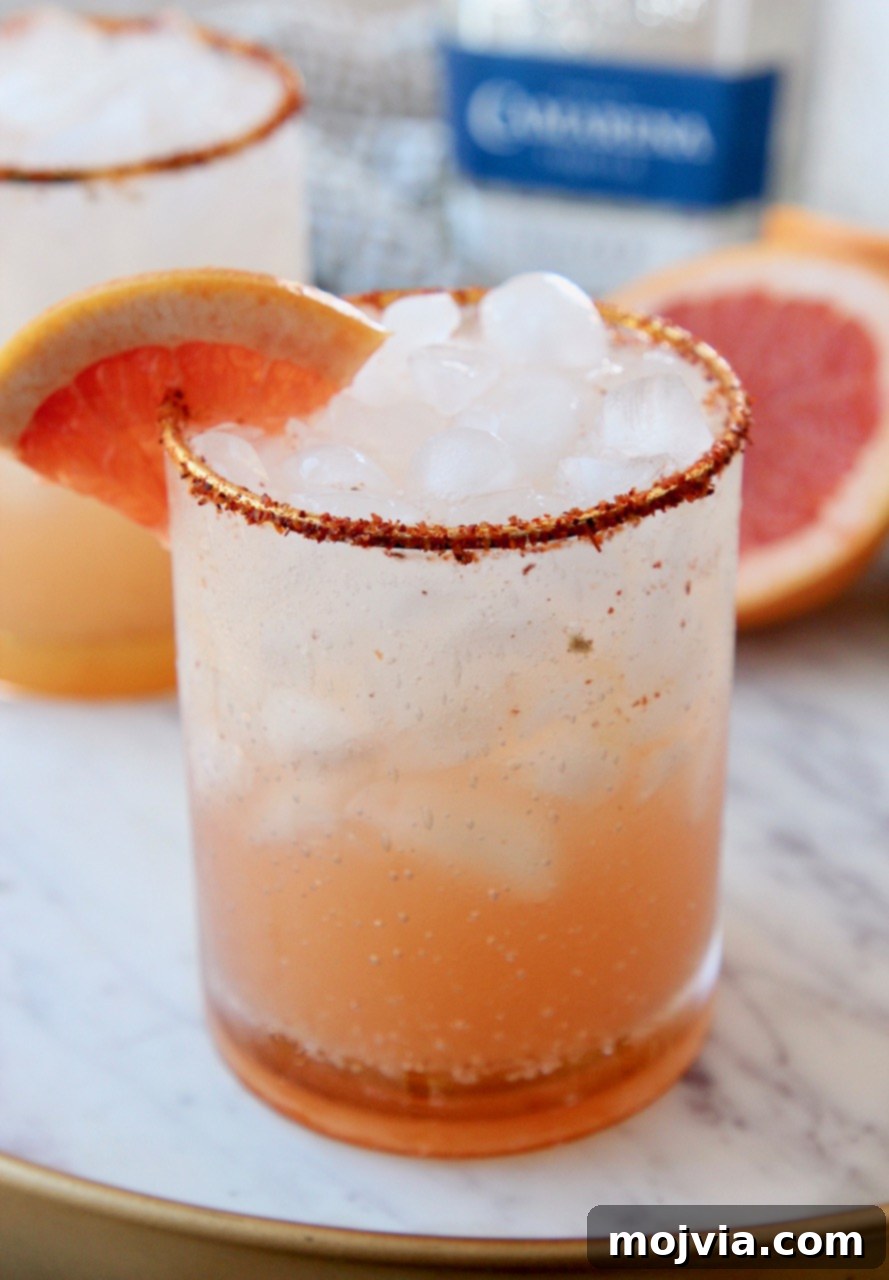 Whispers of Paloma 6 Paloma cocktail in a highball glass with a Tajin rim and a fresh grapefruit slice garnish
