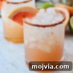 Paloma cocktail in glass with Tajin on the rim and grapefruit wedge on the edge of the glass
