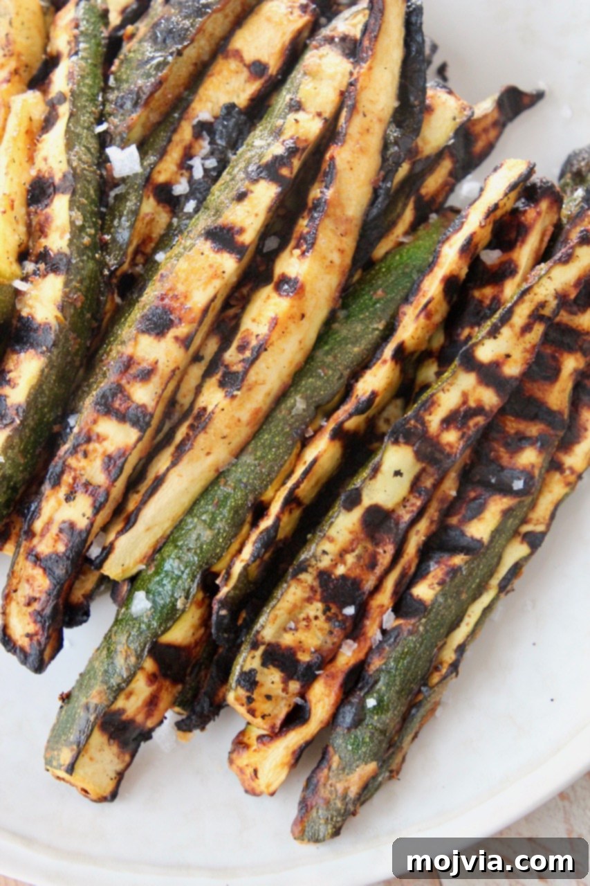 Summer Grilled Zucchini 2 Perfectly grilled zucchini spears with a beautiful char, arranged on a rustic plate, ready to be served as a delicious summer side dish.