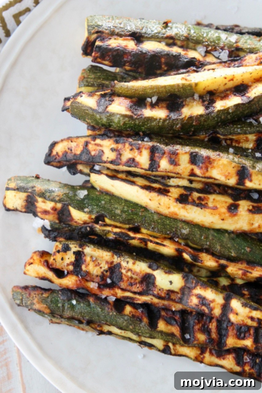 Summer Grilled Zucchini 5 Close-up of golden-brown grilled zucchini spears, perfectly charred and tender, arranged artfully on a plate for serving.