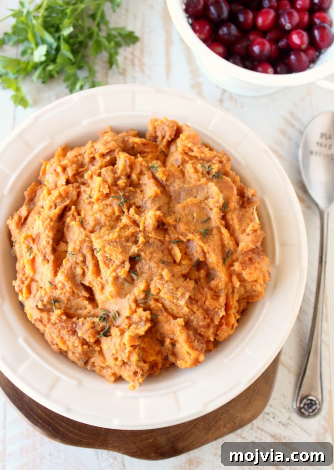 creamy mashed sweet potatoes in a white bowl, garnished with a sprinkle of cinnamon