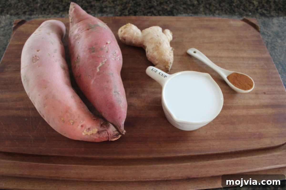 close-up of raw sweet potatoes, coconut milk, cinnamon sticks, and fresh ginger root on a wooden board
