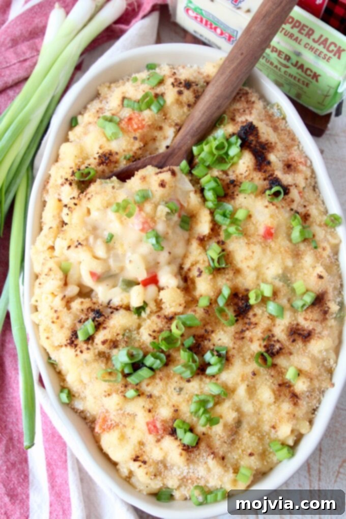Bayou Blend Mac and Cheese 6 Oval serving dish filled with creamy Cajun Mac and Cheese, with a serving spoon resting in it, highlighting its rich texture.