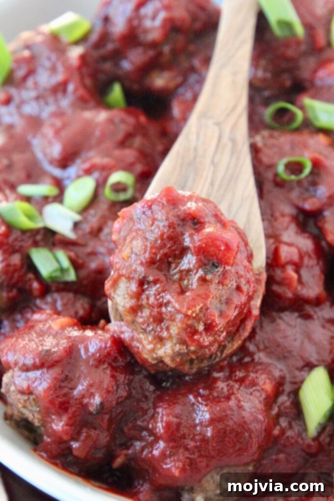 Red Wine Infused BBQ Beef Meatballs 2 meatballs with bbq sauce in bowl and meatball on a spoon in the bowl